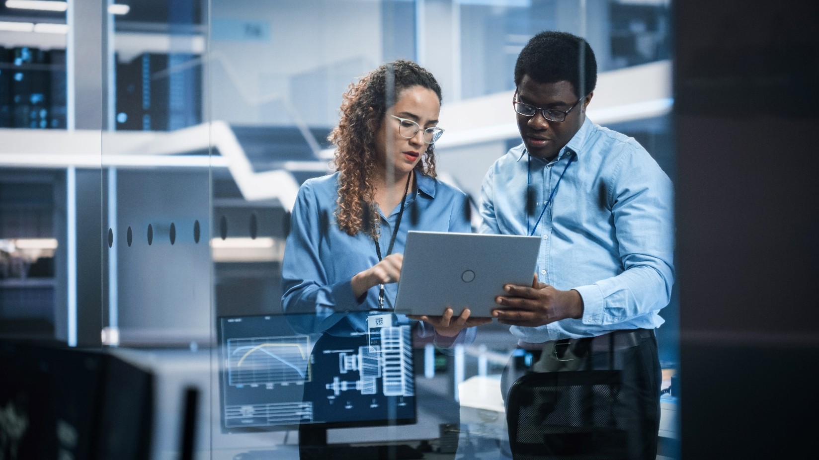 Two skilled foreign workers who work in tech looking at a laptop.