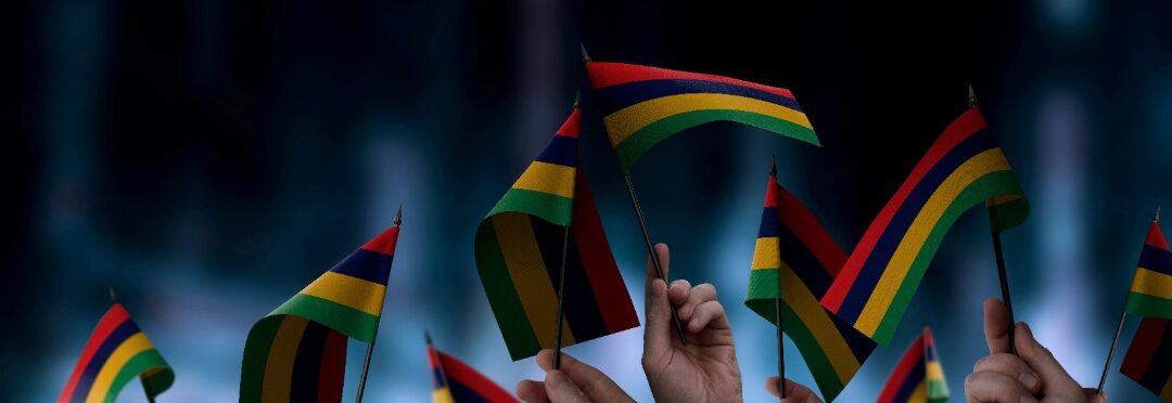 Mauritius flags in their hands on a blurred urban blue background