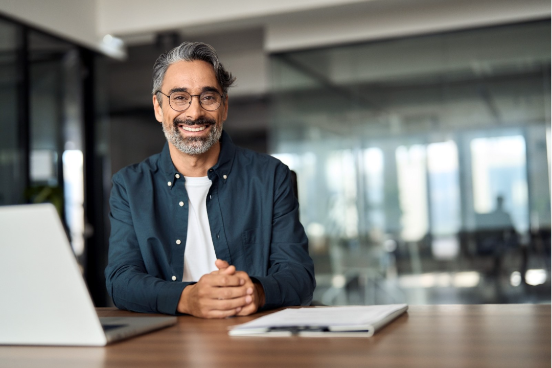 A wealthy man sitting at a desk wearing glasses and learning about the EB-5 Green Card investment.