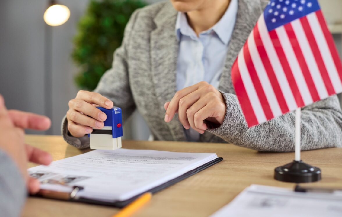 U.S. immigration document being stamped on application paperwork with American flag in background