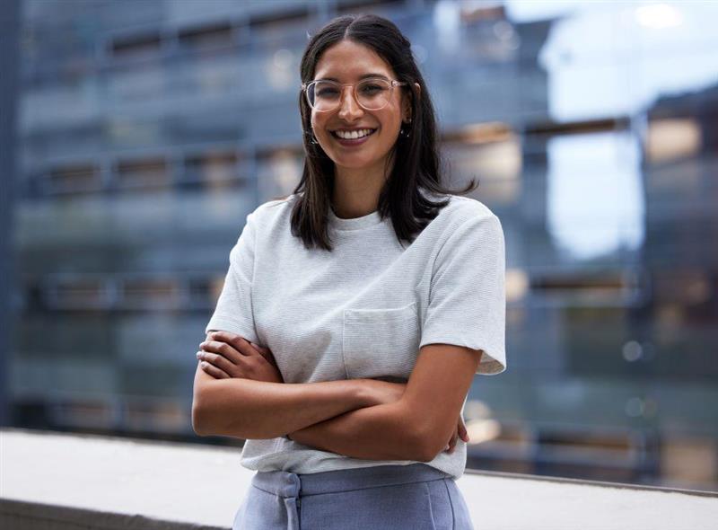 A woman standing with her arms crossed and smiling.