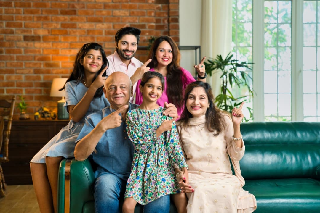 A family including parents, grandparents, and children, sitting on a couch who have immigrated to Canada using the Canada family sponsorship process.