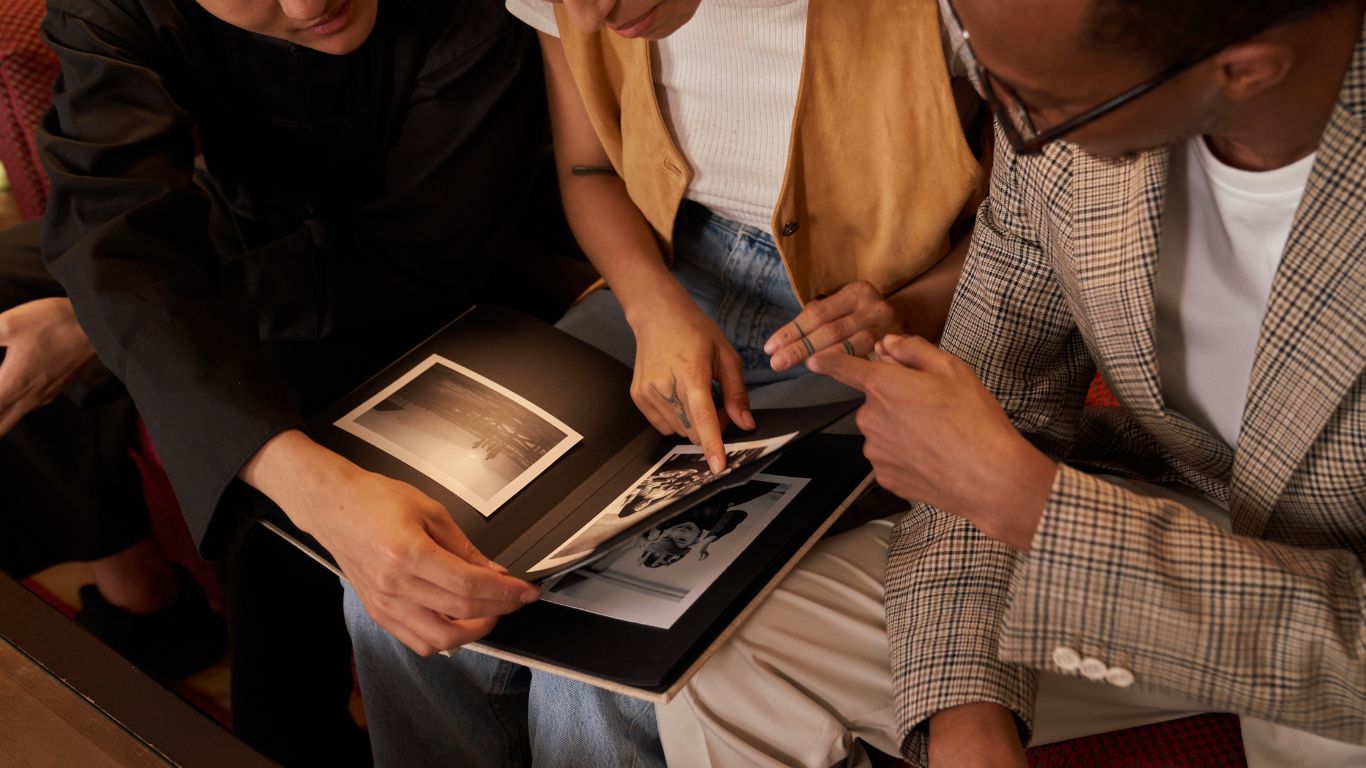 three people seated and viewing a photo album