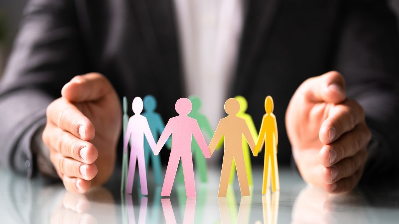 paper cutouts of people on a table in between a person's hands